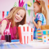 Tüdruk mängutoas sirutab käe maiustuste poole värvilisel peolaual