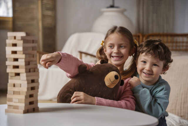 Kaks last mängivad toas puidust klotsidega torni ja hoiavad kaisukaru